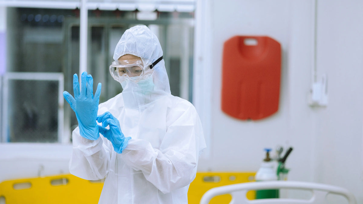 Worker wearing personal protective equipment including safety goggles, protective clothing, face covering, and gloves.